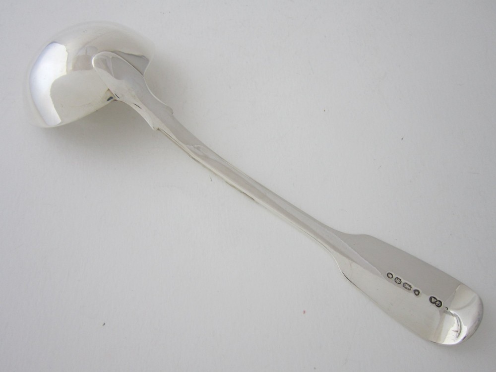 A Victorian sterling silver sauce ladle featuring a fiddle pattern handle and a round deep bowl, displayed on a plain white surface. View IV