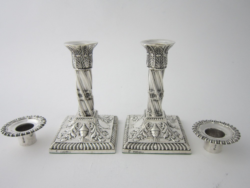 Pair of 1884 Victorian sterling silver candlesticks featuring spiral fluted column stems and square bases embossed with urn and leaf motifs. View II