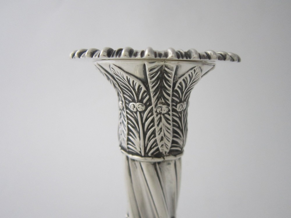 Pair of 1884 Victorian sterling silver candlesticks featuring spiral fluted column stems and square bases embossed with urn and leaf motifs. View V