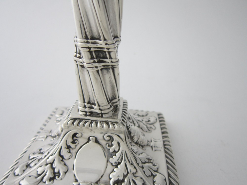 Pair of 1884 Victorian sterling silver candlesticks featuring spiral fluted column stems and square bases embossed with urn and leaf motifs. View VI
