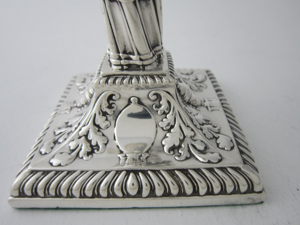 Pair of 1884 Victorian sterling silver candlesticks featuring spiral fluted column stems and square bases embossed with urn and leaf motifs. View VII