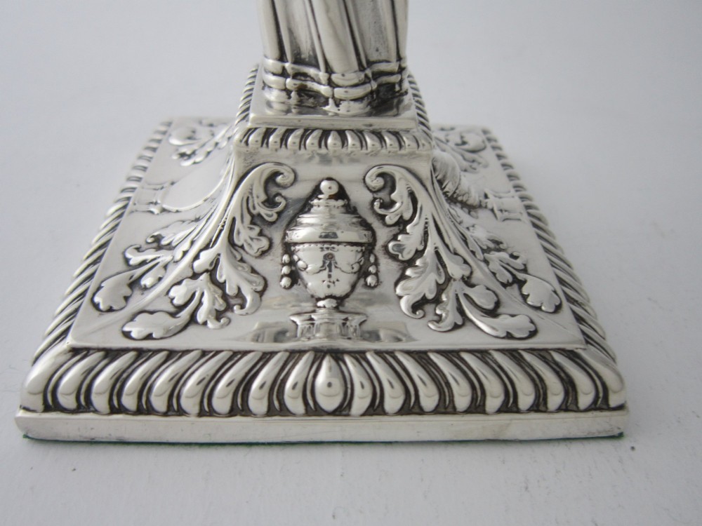 Pair of 1884 Victorian sterling silver candlesticks featuring spiral fluted column stems and square bases embossed with urn and leaf motifs. View VIII