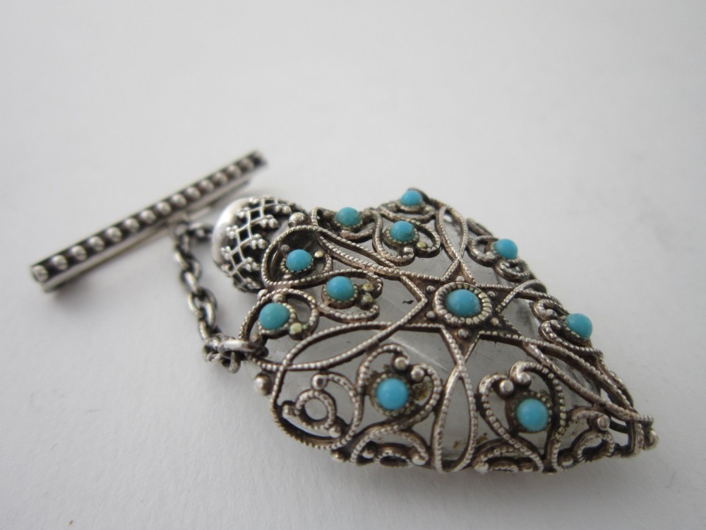A 1920s Continental silver scent bottle featuring clear glass enclosed in silver filigree overlay set with turquoise cabochons, suspended from a beaded bar pin. View II