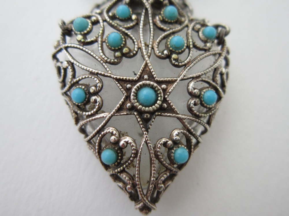 A 1920s Continental silver scent bottle featuring clear glass enclosed in silver filigree overlay set with turquoise cabochons, suspended from a beaded bar pin. View VI
