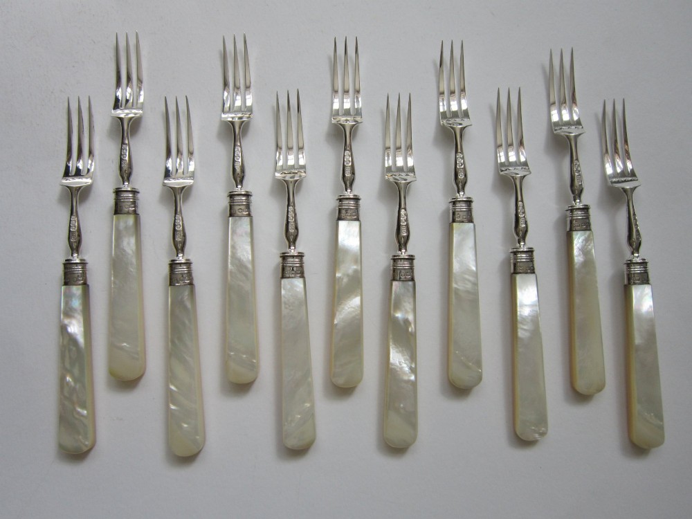 An open fitted wooden canteen displaying a set of sterling silver dessert knives and forks with mother-of-pearl handles set against a green velvet lining. View IV