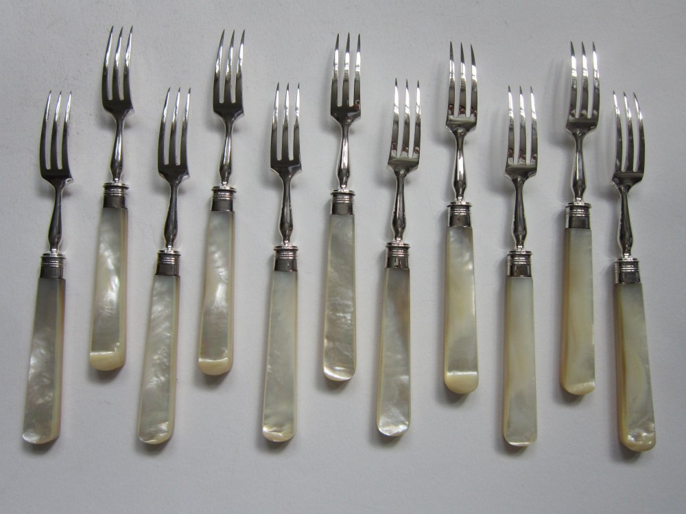 An open fitted wooden canteen displaying a set of sterling silver dessert knives and forks with mother-of-pearl handles set against a green velvet lining. View V