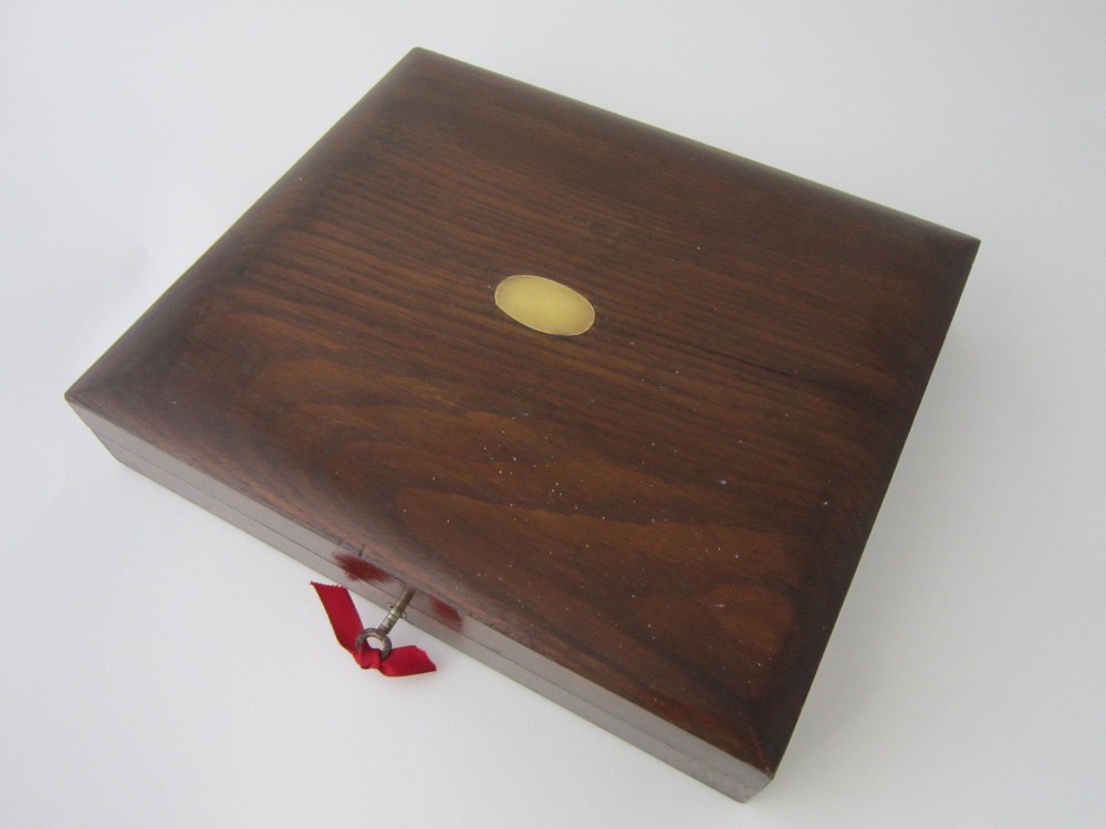 An open fitted wooden canteen displaying a set of sterling silver dessert knives and forks with mother-of-pearl handles set against a green velvet lining. View XII