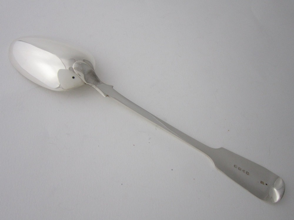 An antique Victorian sterling silver basting spoon featuring a fiddle pattern handle and polished oval bowl. View IV