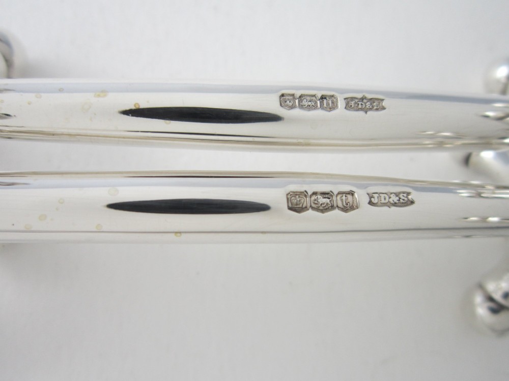 A pair of hallmarked sterling silver knife rests with crossed spherical end supports connected by a smooth central bar. View IV