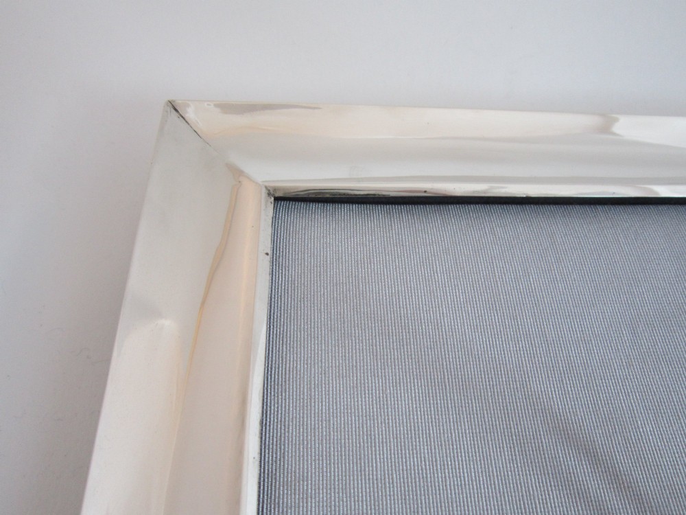 A rectangular George V sterling silver photograph frame with a plain polished moulding presented in a horizontal orientation. View XII