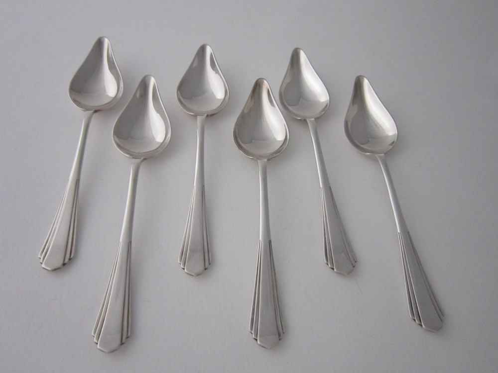 A set of six Art Deco sterling silver grapefruit spoons with pointed bowls and stepped handles displayed in an open presentation case. View II