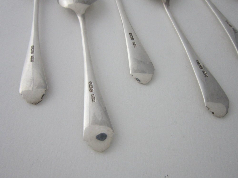 A set of six Art Deco sterling silver grapefruit spoons with pointed bowls and stepped handles displayed in an open presentation case. View VII