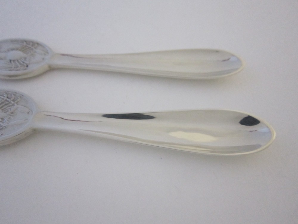 A pair of sterling silver lobster picks with embossed crustacean central medallions displayed inside a fitted black satin and velvet presentation box. View VII