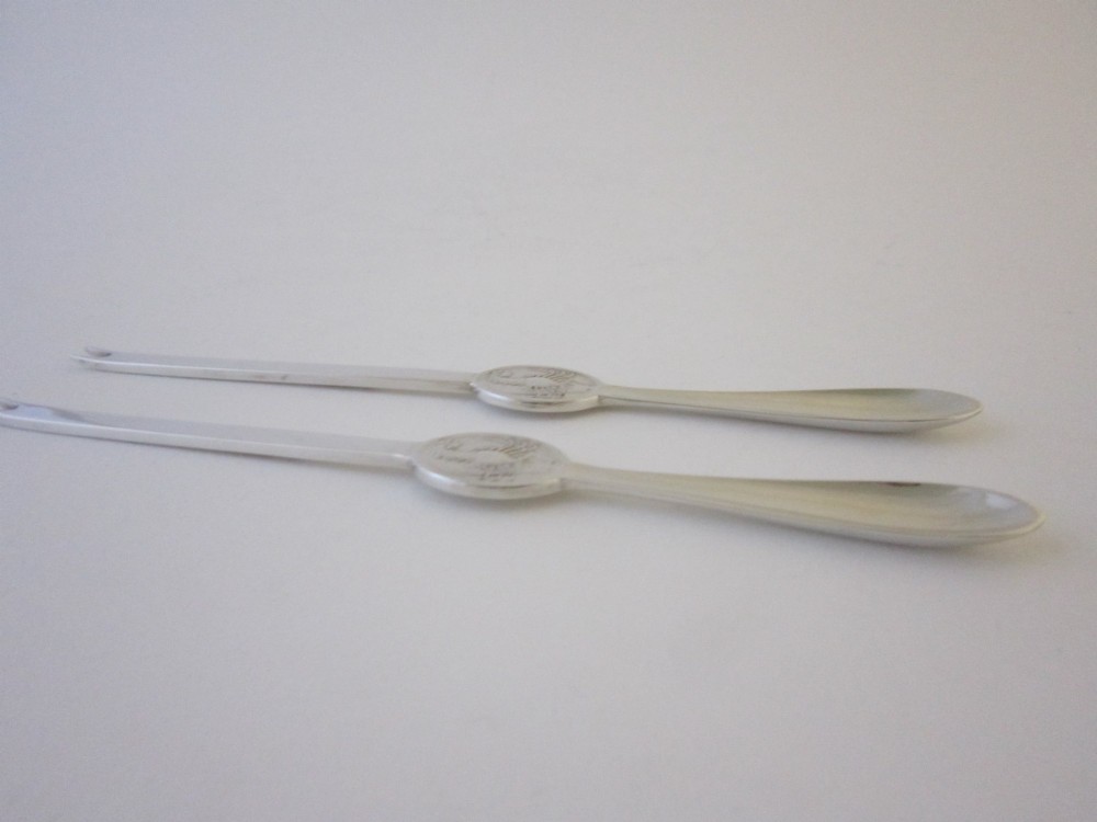A pair of sterling silver lobster picks with embossed crustacean central medallions displayed inside a fitted black satin and velvet presentation box. View VIII