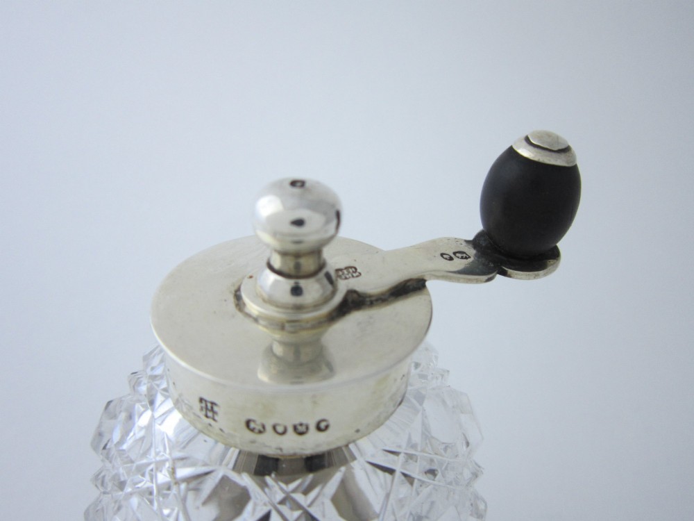 A Victorian sterling silver and cut glass pepper grinder featuring a round glass body, hallmarked silver collar and base, and a top crank handle. View II