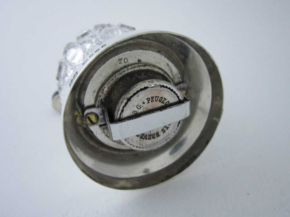 A Victorian sterling silver and cut glass pepper grinder featuring a round glass body, hallmarked silver collar and base, and a top crank handle. View IV