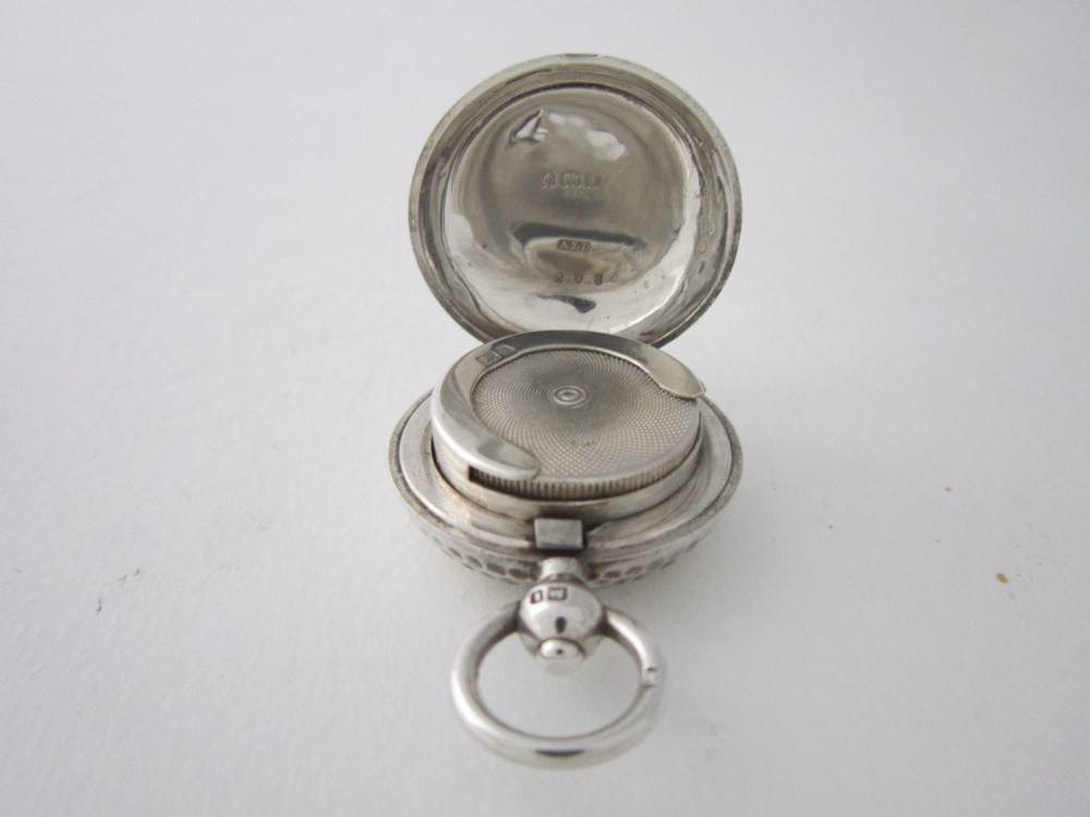 An Edwardian sterling silver sovereign case featuring a hammered circular exterior, a smooth central cartouche, and a top suspension ring. View IV
