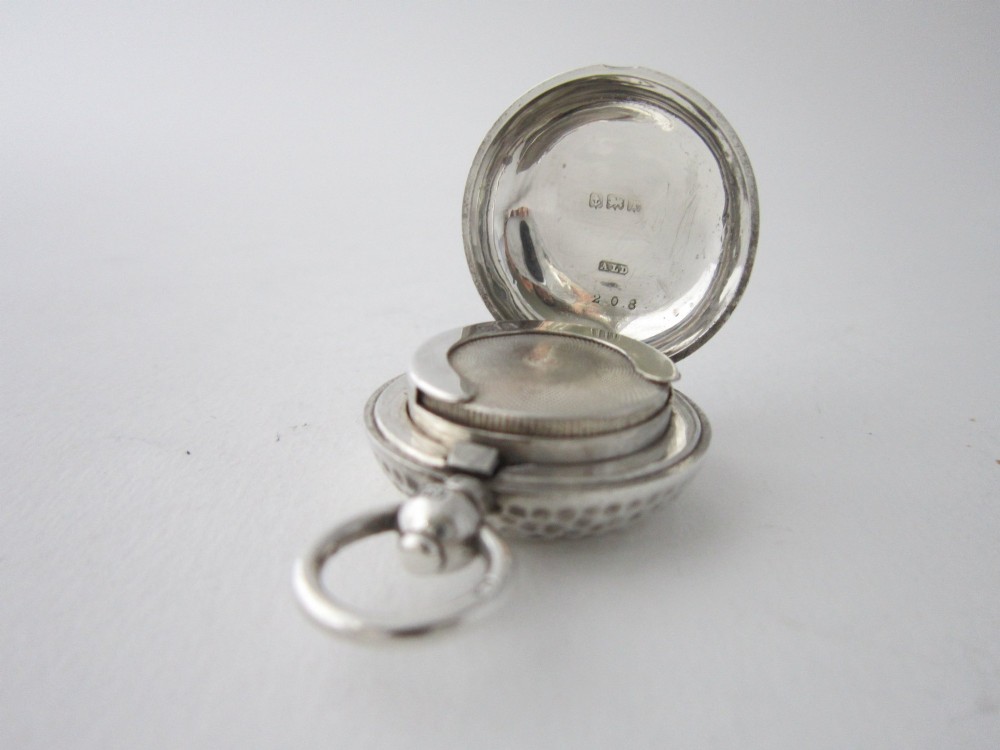 An Edwardian sterling silver sovereign case featuring a hammered circular exterior, a smooth central cartouche, and a top suspension ring. View V