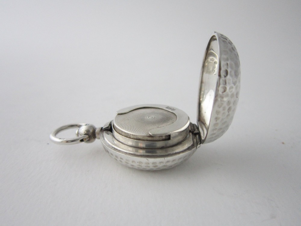 An Edwardian sterling silver sovereign case featuring a hammered circular exterior, a smooth central cartouche, and a top suspension ring. View VI