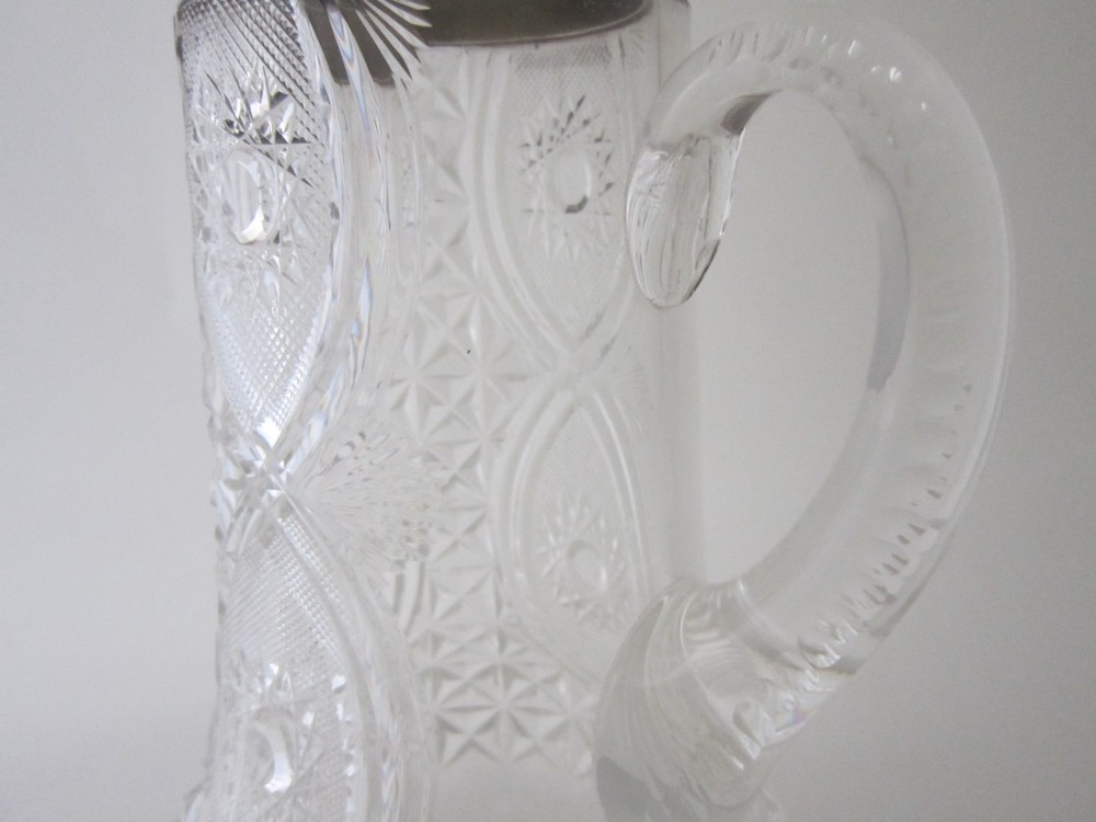 A large George V cut glass jug featuring a sterling silver collar and spout alongside a moulded glass handle. View IV