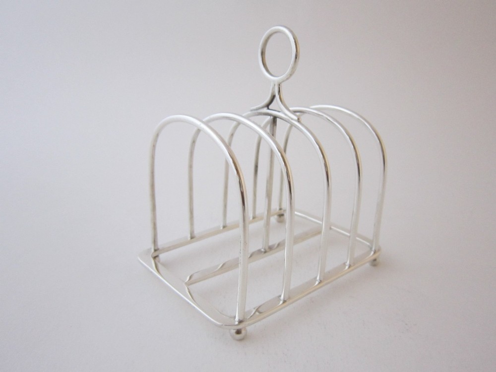 A Victorian sterling silver toast rack with five arched wire partitions, a top ring handle, and small ball feet. View III