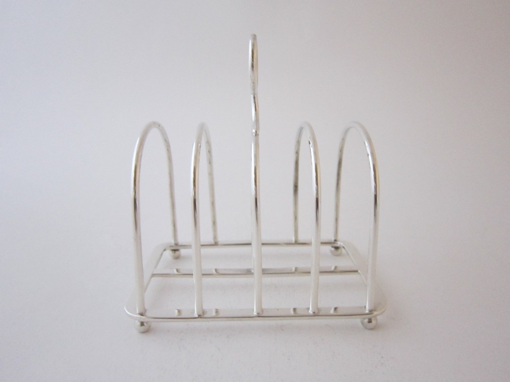 A Victorian sterling silver toast rack with five arched wire partitions, a top ring handle, and small ball feet. View IV