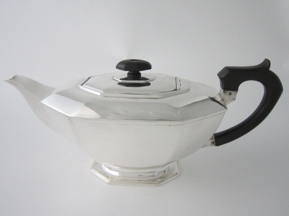 An octagonal sterling silver teapot featuring an ebonised wooden handle and matching black lid finial.