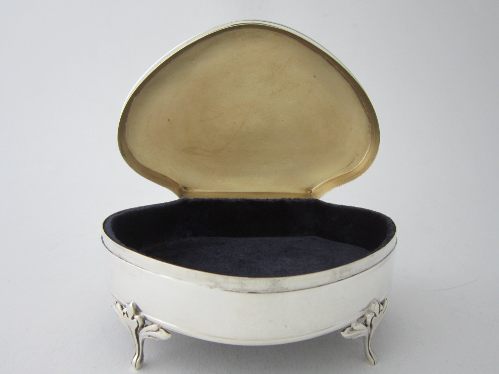 A kidney-shaped antique sterling silver trinket box with a beaded edge hinged lid standing on small decorative feet. View II