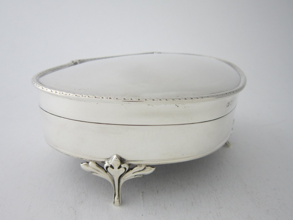 A kidney-shaped antique sterling silver trinket box with a beaded edge hinged lid standing on small decorative feet. View III