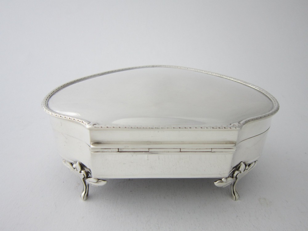 A kidney-shaped antique sterling silver trinket box with a beaded edge hinged lid standing on small decorative feet. View IV