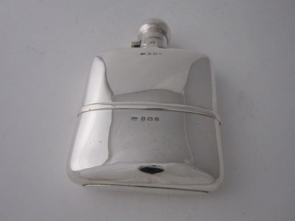 A curved sterling silver hip flask with a bayonet cap and stamped British hallmarks. View V