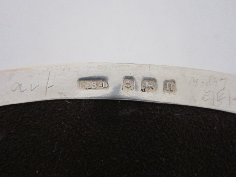 An oval sterling silver trinket box featuring a dark tortoiseshell lid inlaid with a silver wire floral basket and ribbon motif, set on small feet. View VIII