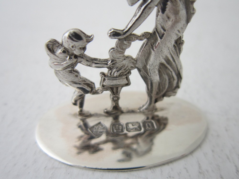 A pair of Edwardian sterling silver place card holders featuring classical female figures and cherubs on round hallmarked bases. View VI