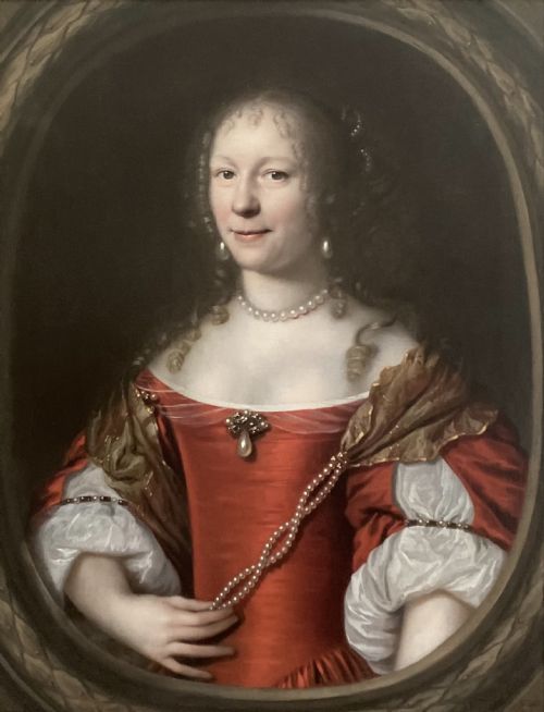 fig 1. An oil portrait of a lady in a red dress with pearl jewellery set inside a carved giltwood frame.