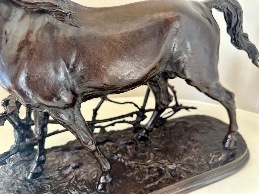 A dark brown 19th-century bronze sculpture of a horse stepping over a wooden hurdle fence mounted on an oval bronze base. View VII
