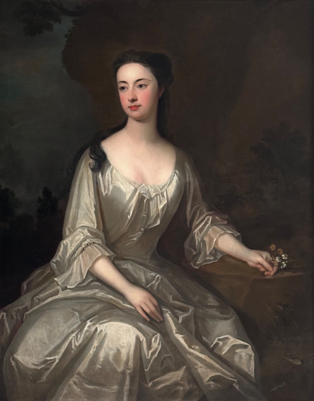 An early eighteenth-century oil painting on canvas depicting a seated lady in a silk gown within a carved giltwood frame. View II