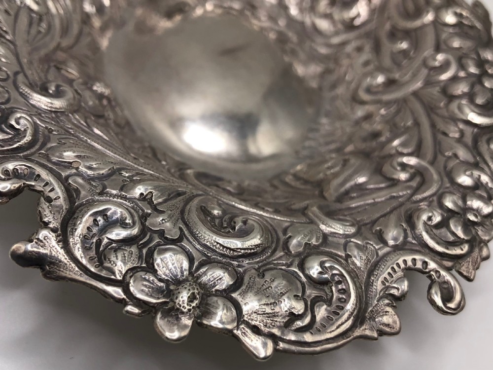 An oval Victorian sterling silver dish with detailed repousse floral motifs and a scalloped scrolling edge. View III