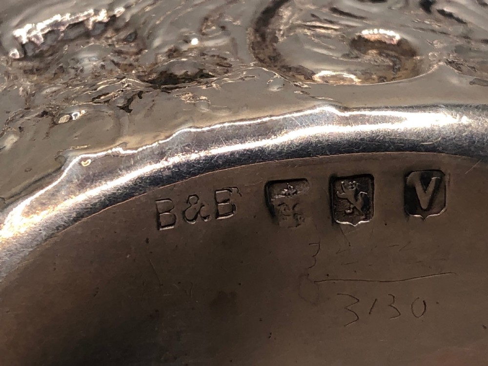 An oval Victorian sterling silver dish with detailed repousse floral motifs and a scalloped scrolling edge. View IV