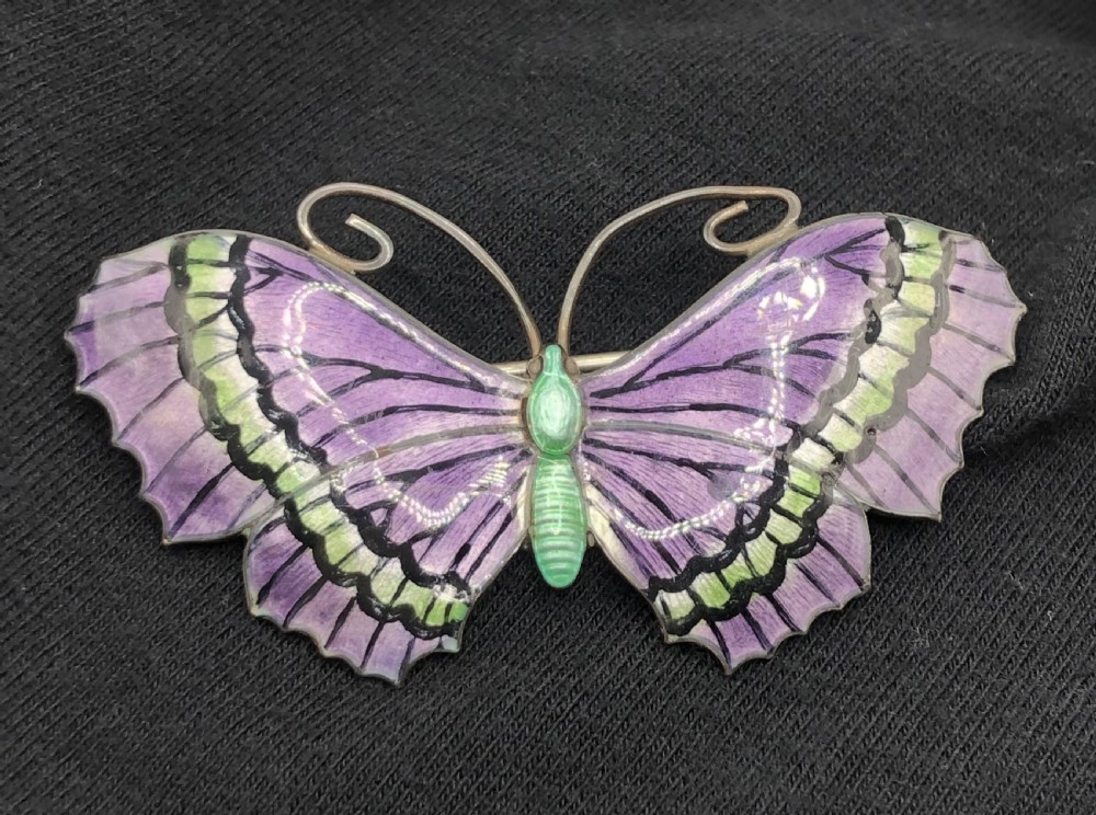 A silver butterfly brooch featuring purple and green guilloche enamel wings with black details and coiled wire antennae. View III