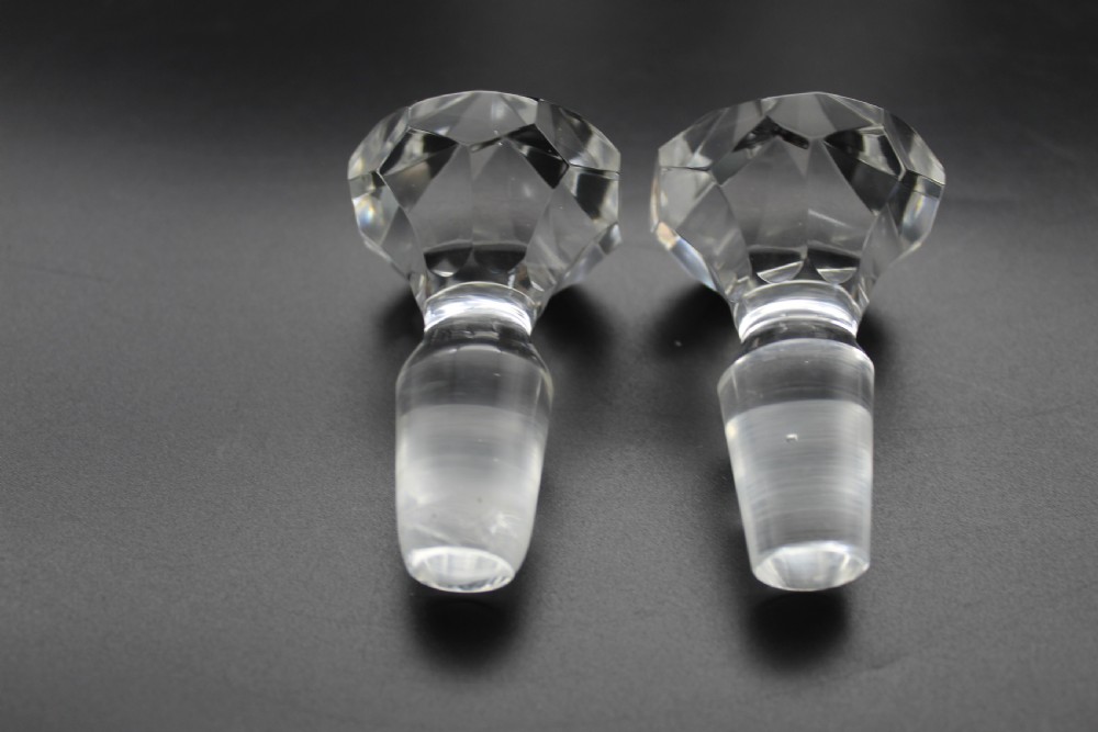 A pair of 19th-century clear cut glass decanters featuring three applied neck rings, geometric diamond cutting, and faceted stoppers. View VI