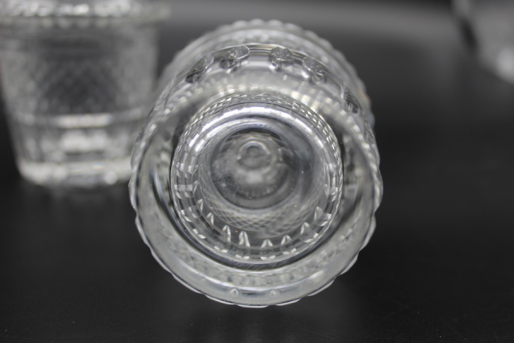 A pair of 19th-century clear cut glass decanters featuring three applied neck rings, geometric diamond cutting, and faceted stoppers. View VII