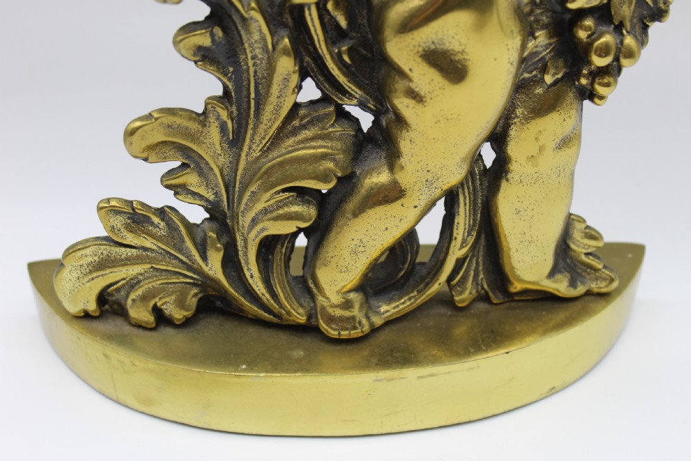 A Victorian cast brass doorstop featuring a standing winged cherub amidst acanthus leaf scrolls topped with a curved carrying handle. View IX