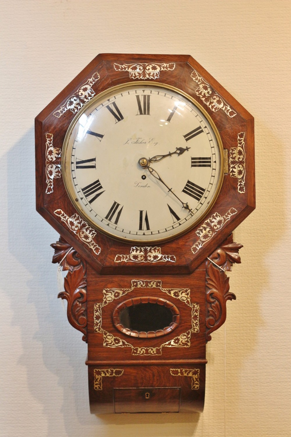 A nineteenth-century Victorian octagonal rosewood wall clock featuring scrollwork inlay, carved side brackets, and a white dial with Roman numerals.