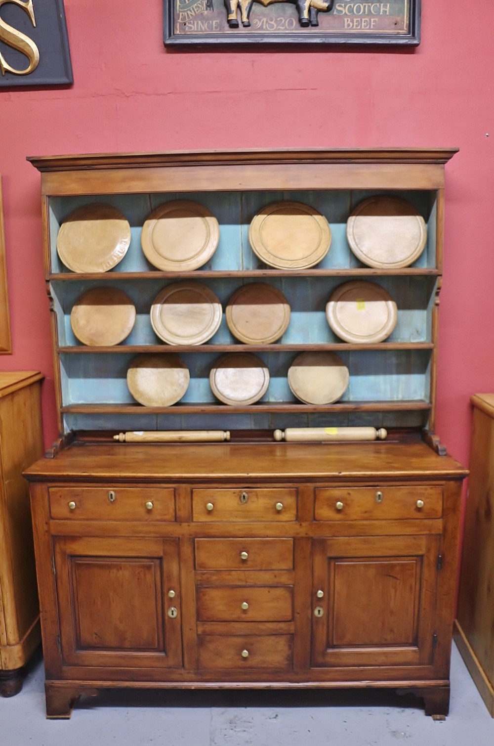 An eighteenth-century warm pine Welsh dresser featuring an upper three-tier plate rack with painted blue backboards above a base with drawers and panelled doors.