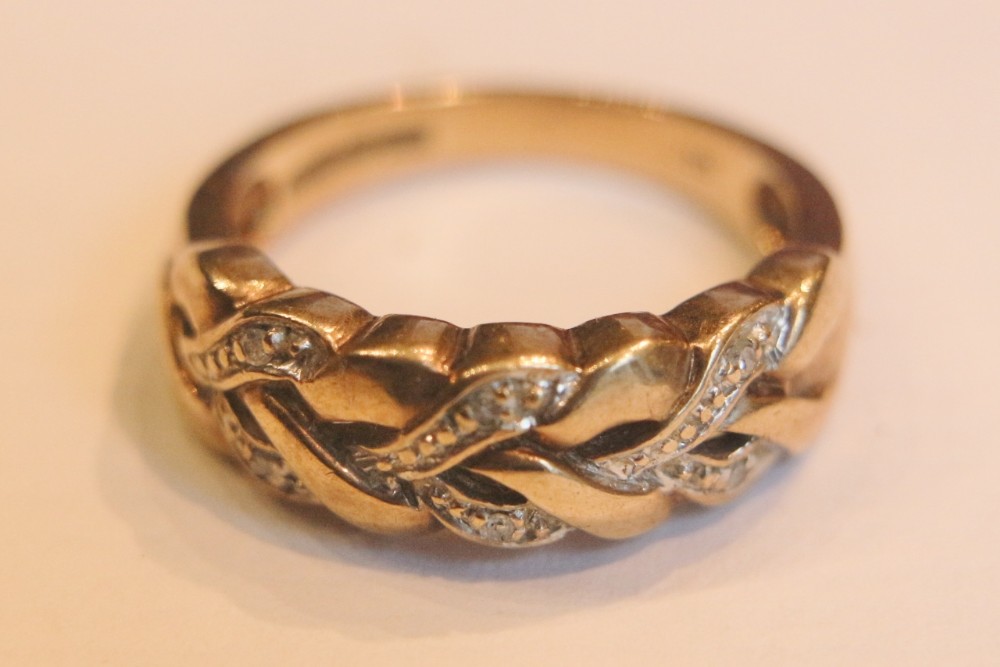 An Edwardian 9 carat yellow gold ring featuring a woven plaited design set with small round diamonds.