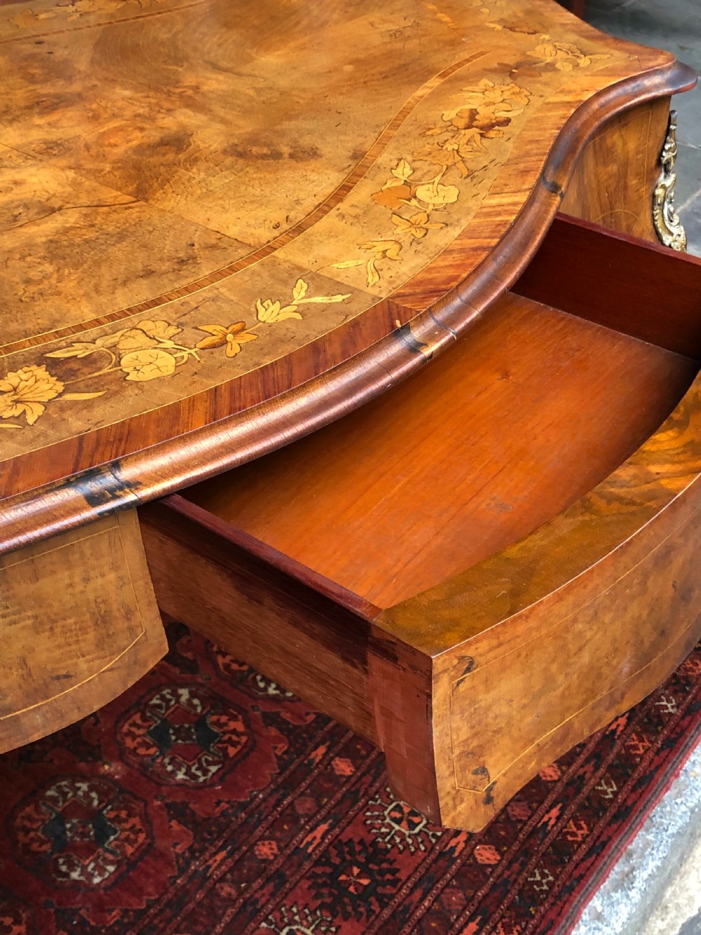 A 19th-century French Louis XV style inlaid writing desk featuring floral marquetry, a serpentine top, cabriole legs, and gilt-bronze mounts. View III