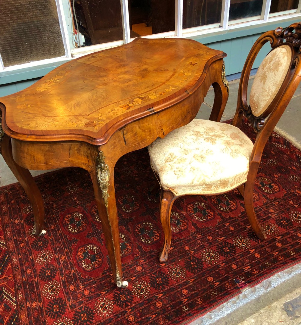 A 19th-century French Louis XV style inlaid writing desk featuring floral marquetry, a serpentine top, cabriole legs, and gilt-bronze mounts. View V