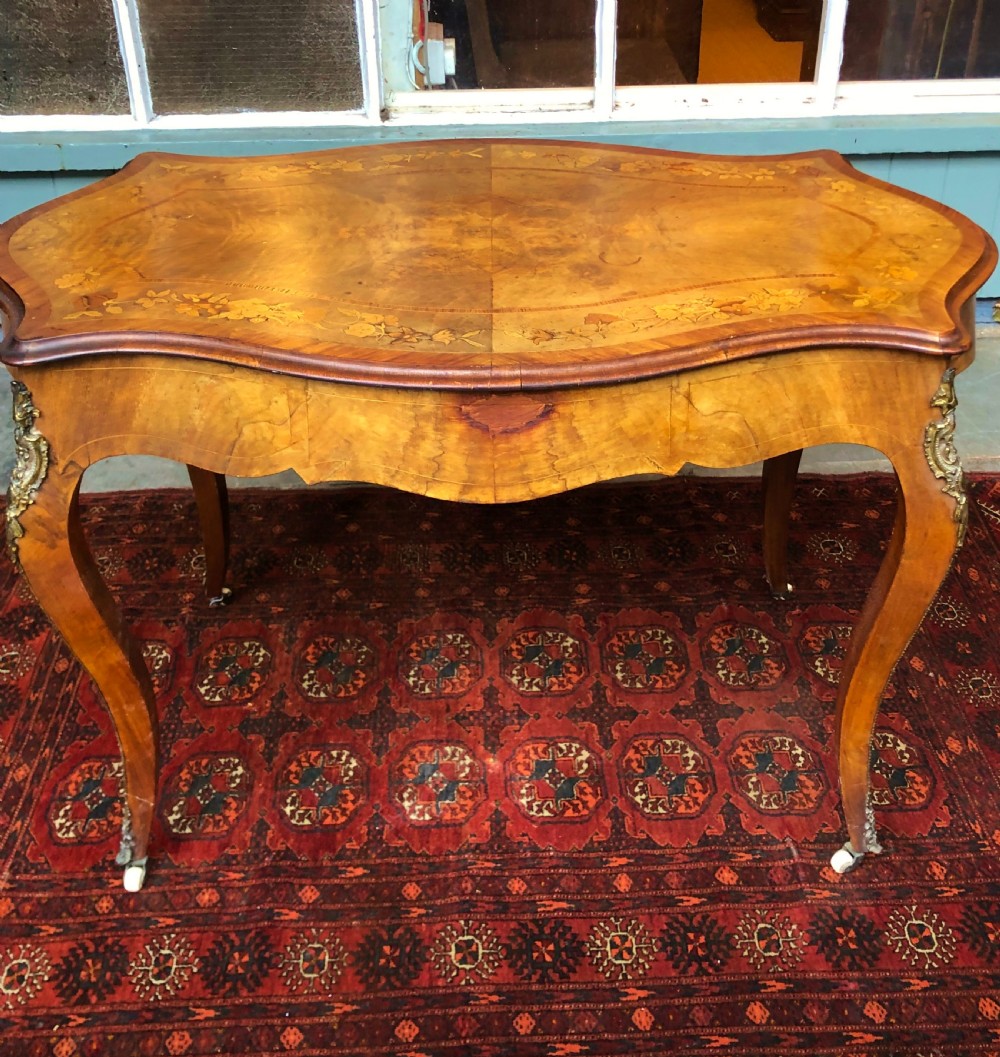A 19th-century French Louis XV style inlaid writing desk featuring floral marquetry, a serpentine top, cabriole legs, and gilt-bronze mounts. View XII