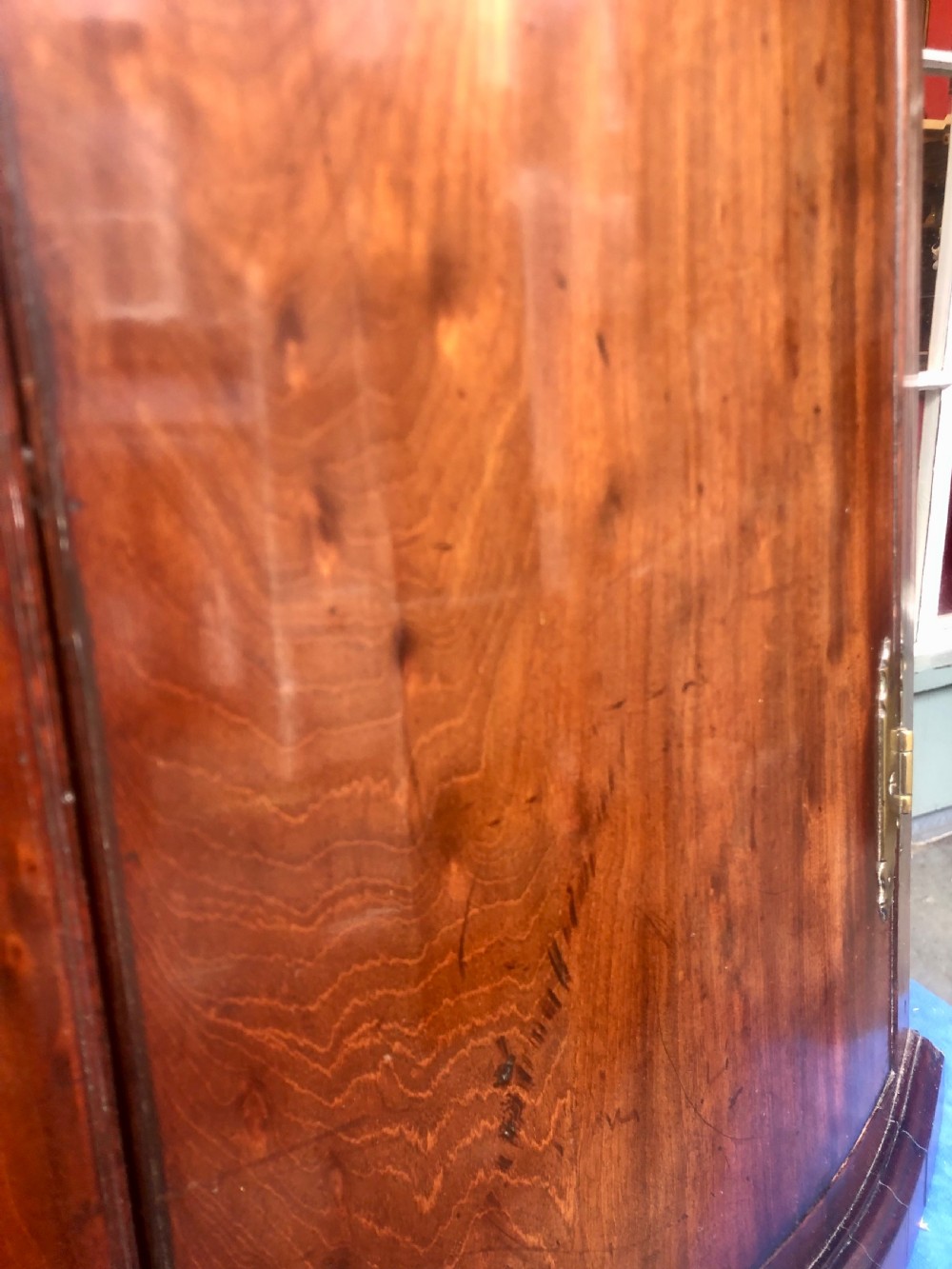 A Georgian bow-fronted mahogany corner cupboard with double doors, brass keyhole escutcheons, and visible brass hinges. View V