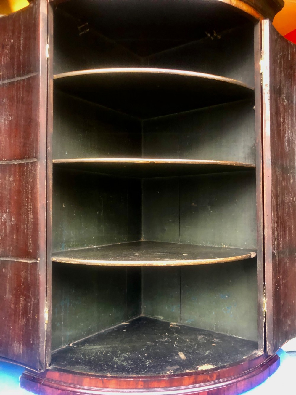 A Georgian bow-fronted mahogany corner cupboard with double doors, brass keyhole escutcheons, and visible brass hinges. View VII